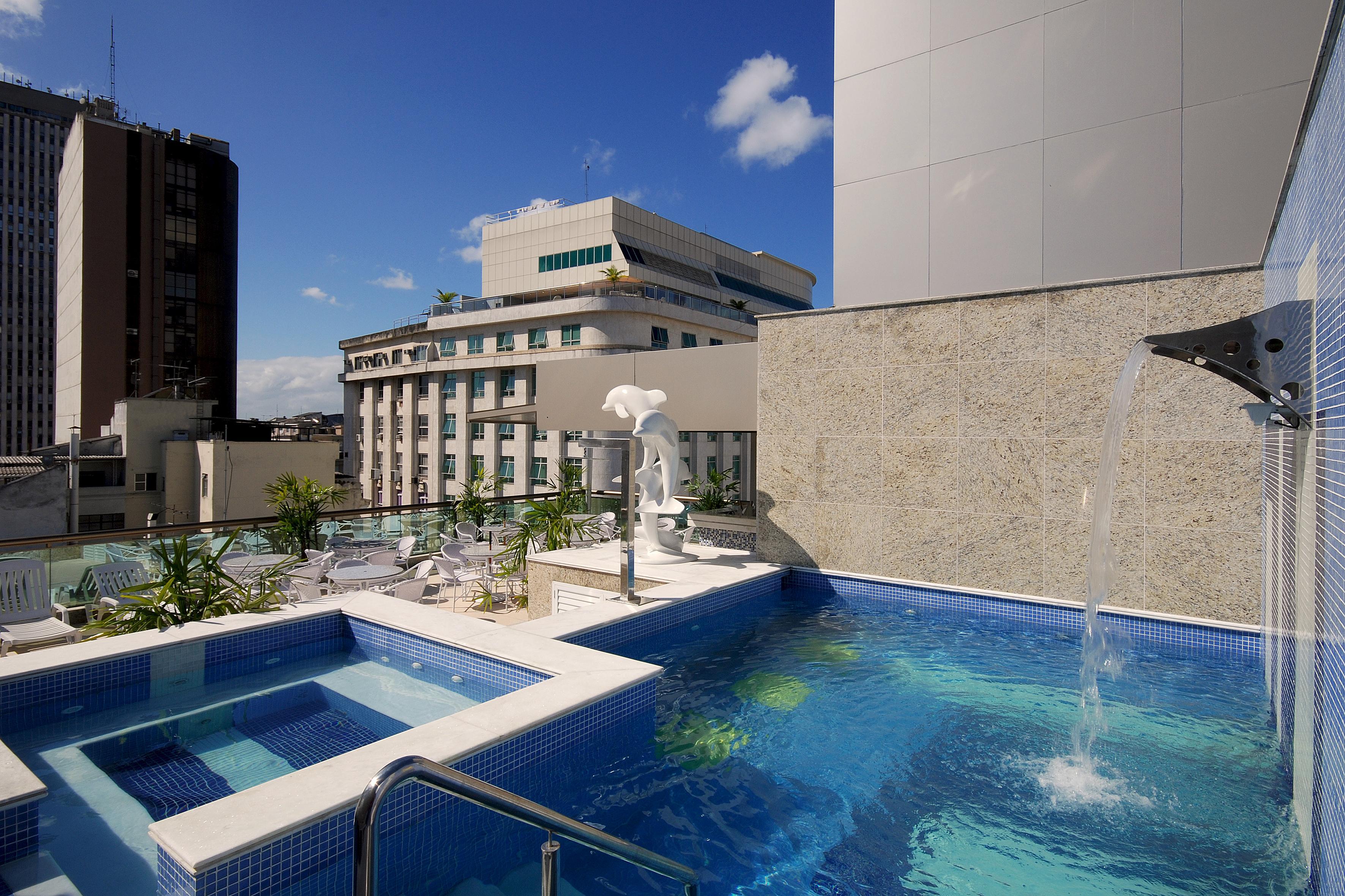 Hotel Atlantico Business Centro Rio de Janeiro Buitenkant foto The photo shows a rooftop area featuring a swimming pool and a spa. The pool is inviting with a clear blue water, and there appears to be a waterfall feature. Surrounding the pool are areas for relaxation, possibly with sun loungers. In the backgroun